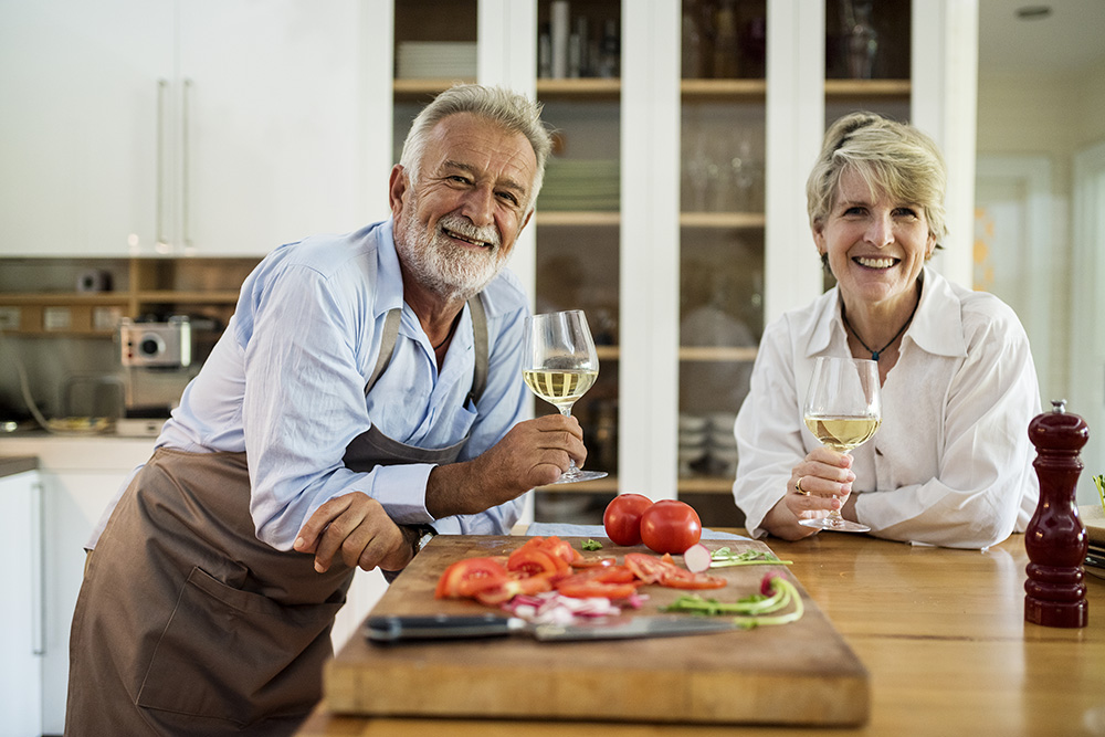 Senior couple enjoying white wine in the kitchen